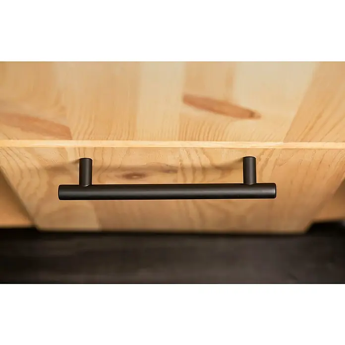 Rei Möbelgriff - Lochabstand: 128 mm, Stahl, Schwarz, Rund, L x B x H: 168 x 12 x 32 mm - Matter schwarzer zylindrischer Griff an einer hellen Holzschublade.