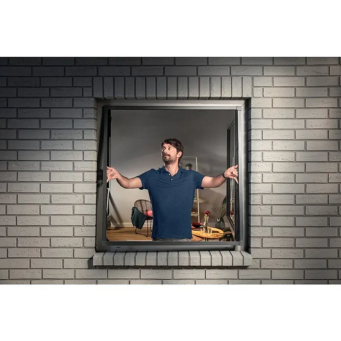 Tesa Insektenschutzfenster FALT für Fenster - Weiß, Montage Insektengitter: Klemmen - Mann verstellt ein dunkelgraues Fliegengitter in einem Fenster.