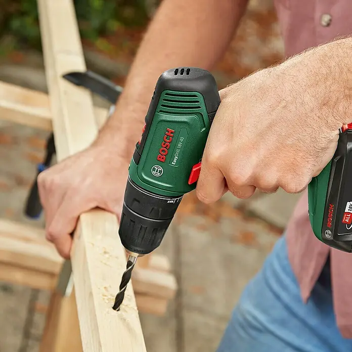 Bosch Power for All 18V Akku-Bohrschrauber Easy Drill 18V-40 - 18 V, 2 Akkus, 1,5 Ah, 32 Nm - Grüner und schwarzer Bosch EasyDrill 18V-40 Akkubohrschrauber, in Händen, bohrt in helles Holz.