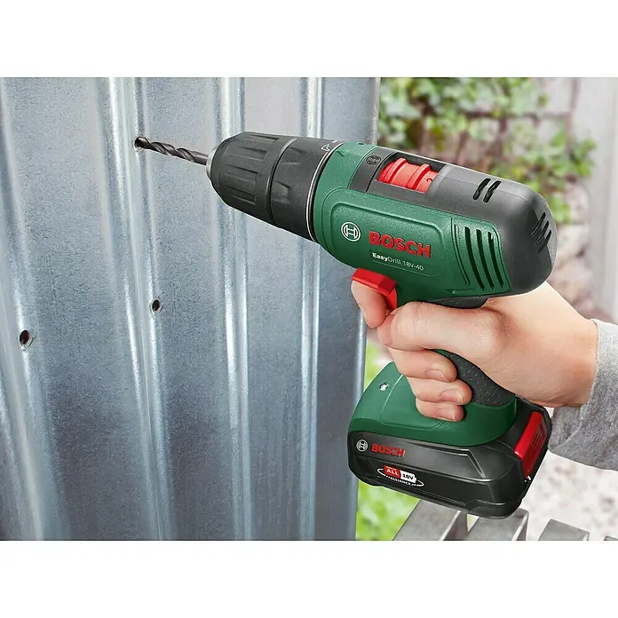Bosch Power for All 18V Akku-Bohrschrauber EasyDrill 18V-40 - 18 V, 1 Akku, 1,5 Ah, 32 Nm - Grün-schwarzer Bosch EasyDrill 18V-40 Akkubohrschrauber, von Hand gehalten, bohrt ein Loch in Wellblech.