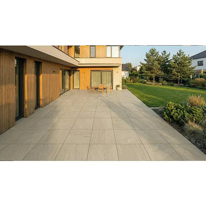 Terrassenfliese Tempio - 60 x 60 x 2 cm, Beige, Matt - Große Terrasse aus hellgrauen Pflasterplatten in Natursteinoptik, neben einem modernen Haus.