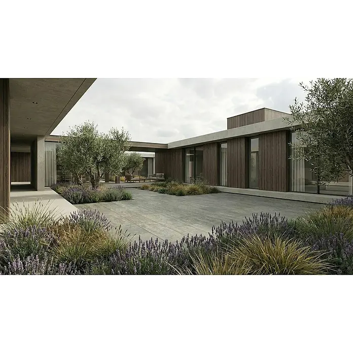 Granulati Zandobbio Terrassenfliese Torre - 40 x 80 x 2 cm, Luserna Mista, Matt - Moderner Innenhof mit großen grauen Terrassenplatten, umgeben von einem Gebäude mit Holzverkleidung, Lavendel und Olivenbäumen.