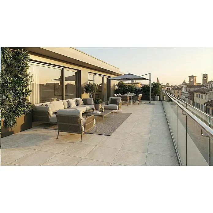 Terrassenfliese Colosseo - 60 x 60 x 2 cm, Barge, Matt - Große Außenterrasse mit hellen, strukturierten rechteckigen Fliesen, ausgestattet mit Lounge- und Essbereichen und Stadtblick.