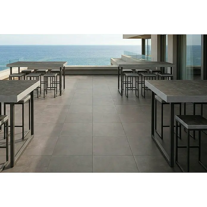 Granulati Zandobbio Terrassenfliese Urban Pro - 60 x 60 x 2 cm, Anthrazit, Matt - Große graue Outdoor-Feinsteinzeugfliesen auf einer modernen Terrasse mit Meerblick und Bartischen.