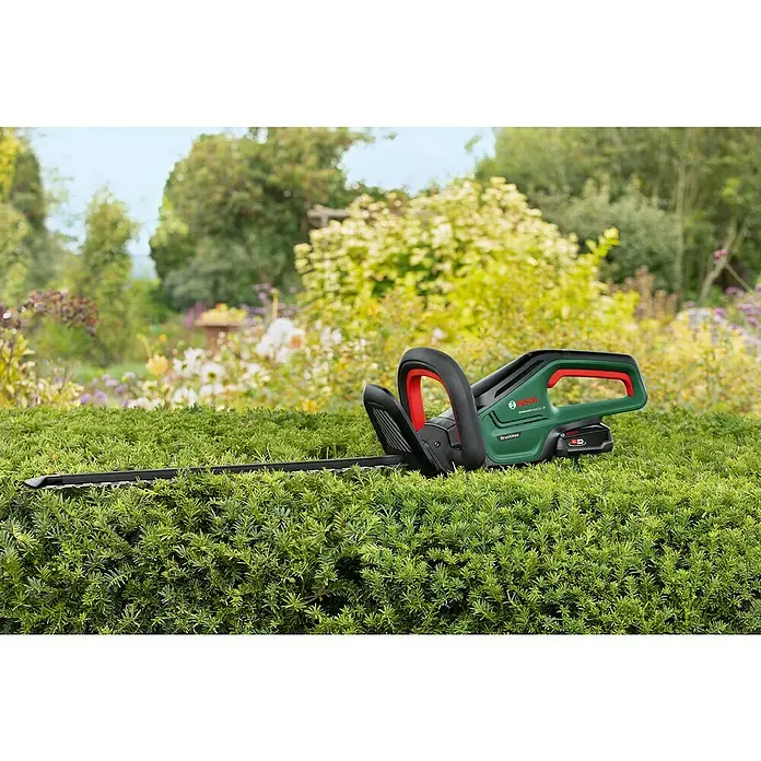 Bosch Power for All 18V Akku-Heckenschere UniversalHedgeCut 18V-50 - 2,5 V, Li-Ionen, Ohne Akku, Schnittlänge: 50 cm - Eine grüne und schwarze Bosch Heckenschere mit roten Akzenten ruht auf einer ordentlich geschnittenen grünen Hecke.