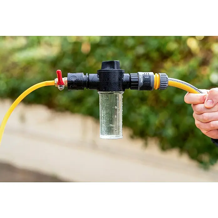 Neptun PV-  & Fassaden Reinigungsset mit verschiedenen Aufsätzen - Teleskopstiel, 120 cm - 490 cm - Schwarzer Kunststoff-Inline-Filter/Spender mit transparentem Messbehälter und rotem Ventil, an gelbem Gartenschlauch gehalten.