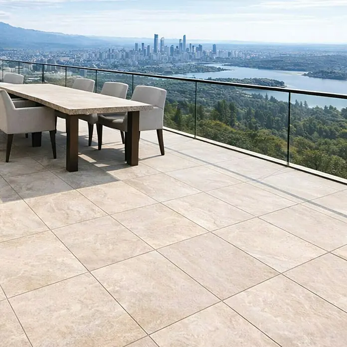 Terrassenfliese Colosseo - 60 x 60 x 2 cm, Barge, Matt - Hellbeige Outdoor-Terrassenfliesen mit Natursteinoptik, verlegt auf einem großen Balkon mit Stadtblick.