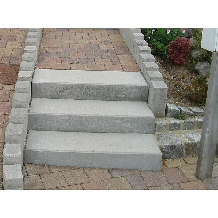 EHL Blockstufe - Grau, 75 x 35 x 15 cm, Beton - Drei graue Betonstufen führen nach oben, gesäumt von Pflastersteinen und kleinen Betonblöcken.