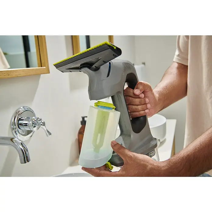Ryobi ONE+ Akku-Fenstersauger RWV18-0 - 18 V, Ohne Akku - Eine Person füllt oder entleert den durchsichtigen Behälter eines grau-schwarzen Hand-Fenstersaugers im Badezimmer.