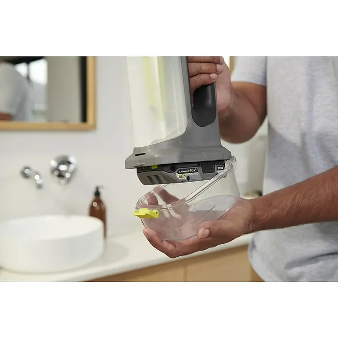 Ryobi ONE+ Akku-Fenstersauger RWV18-0 - 18 V, Ohne Akku - Mann trennt transparenten Behälter von grauem Handfleckreiniger mit gelben Akzenten, betrieben mit Ryobi 18V Akku.