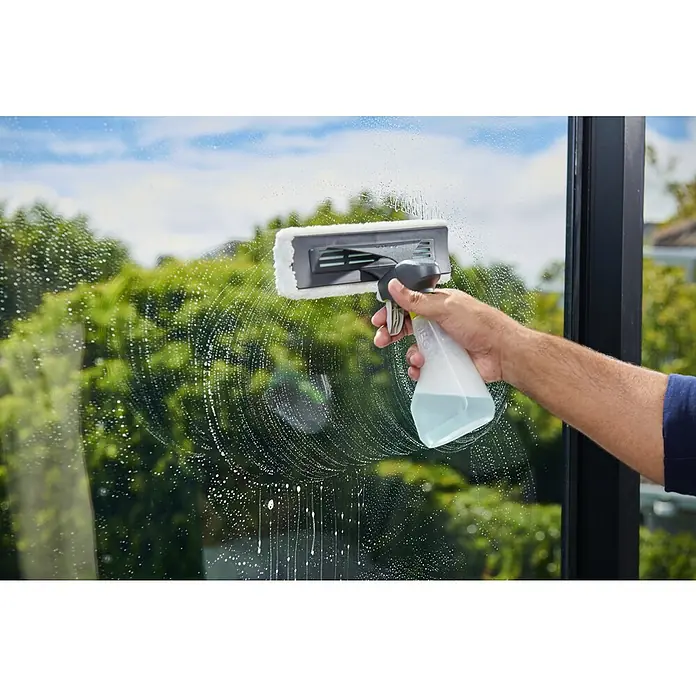 Ryobi ONE+ Akku-Fenstersauger RWV18-0 - 18 V, Ohne Akku - Hand reinigt Fenster mit grau-weißem Fensterwischer und Sprühflasche, Seifenblasen sichtbar.