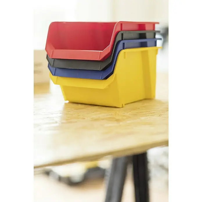 Stanley Sichtlagerkasten - Größe: 3, Rot - Stapel mit farbigen Kunststoffbehältern auf einem Holztisch, ideal für die Werkstattorganisation und Lagerung von Kleinteilen.