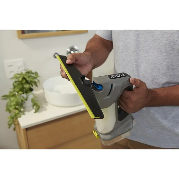 Ryobi ONE+ Akku-Fenstersauger RWV18-0 - 18 V, Ohne Akku - Eine Person hält einen grau-schwarzen Ryobi Fenstersauger mit gelbem Abzieher in einem Badezimmer.