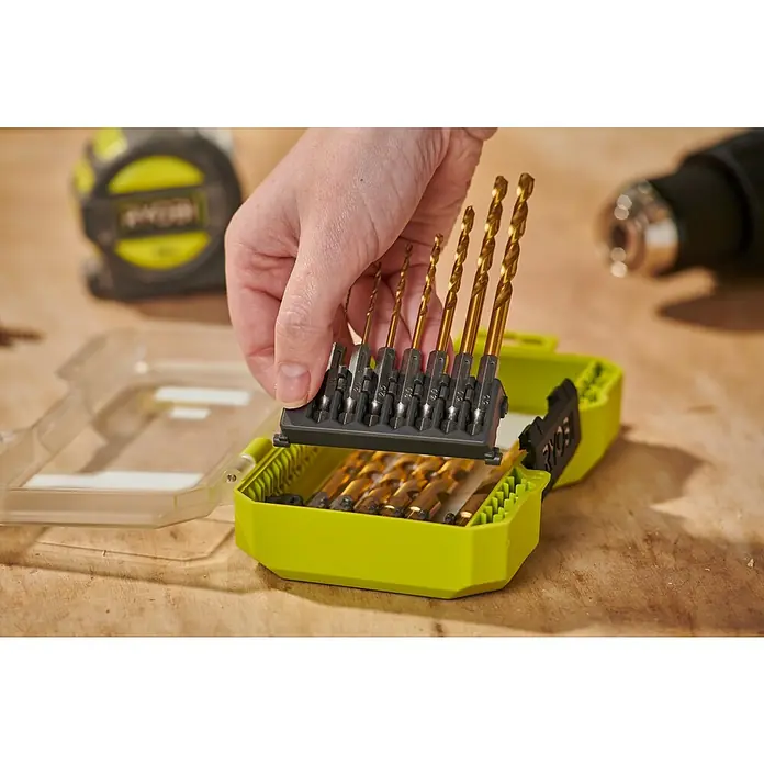 Ryobi Bohrer-Set RARXHG13 - 13 -tlg. - Hand entnimmt goldenen Bohrer aus hellgrüner Box mit verschiedenen Größen, neben Werkzeugen.