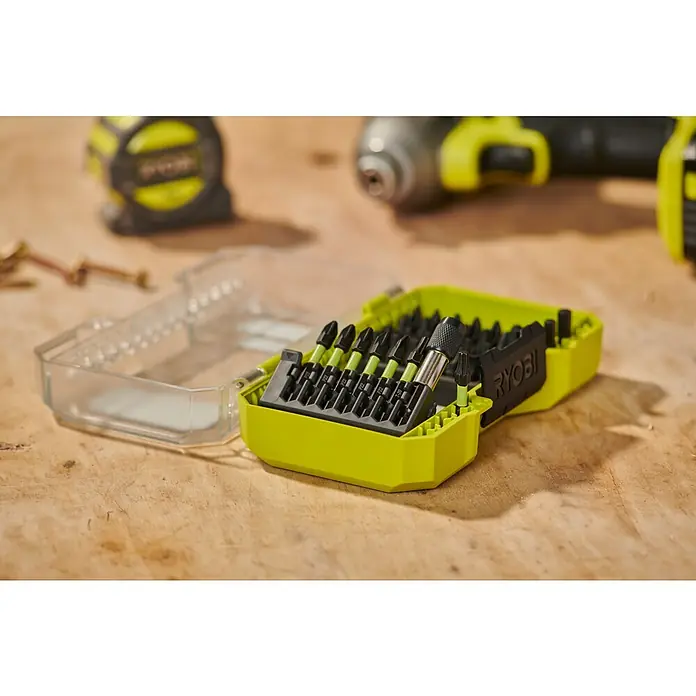 Ryobi Bit-Set RARXSD45 - 45 -tlg. - Geöffnetes Ryobi Schrauberbit-Set in Neongrün und Schwarz mit Bits und Magnethalter auf Holzwerkbank, neben unscharfen Elektrowerkzeugen.