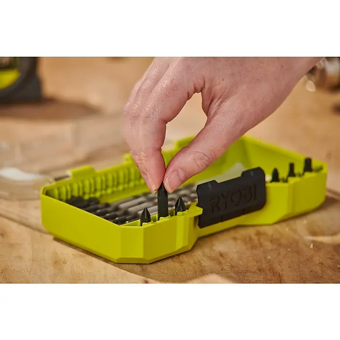 Ryobi Bohrer- & Bit-Set RARXM7 - 13 -tlg. - Hand wählt einen schwarzen Schrauberbit aus einem limettengrünen Ryobi Bit-Set.