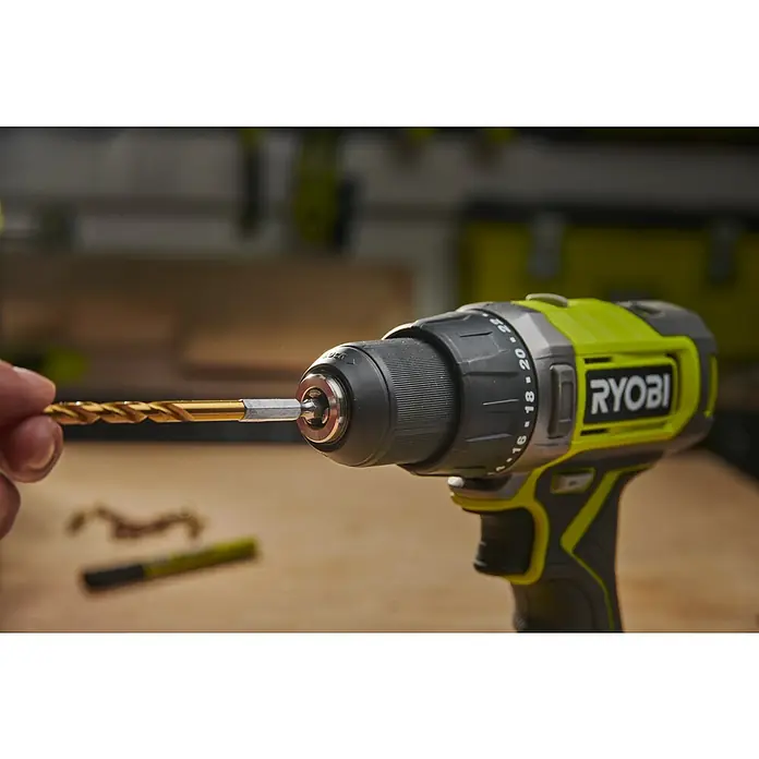 Ryobi Bohrer-Set RARXHG13 - 13 -tlg. - Hand steckt goldenen Bohrer in das Bohrfutter eines grünen und schwarzen Ryobi Akkuschraubers.