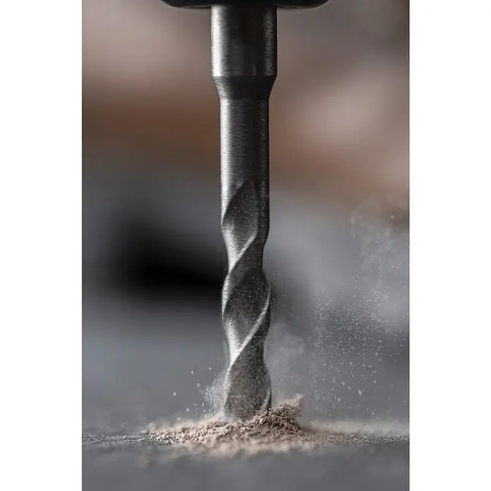 Ryobi Bohrer- & Bit-Set RARXSDS5 - 11 -tlg. - Ein Metallbohrer bohrt in eine dunkle Oberfläche und erzeugt dabei eine Staubwolke.