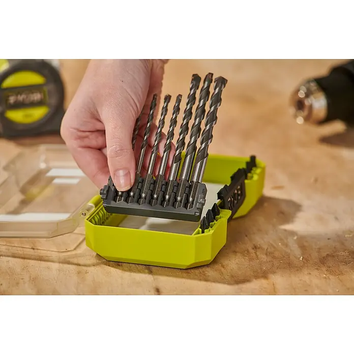 Ryobi Bohrer- & Bit-Set RARXM7 - 13 -tlg. - Hand hält Metallbohrer in schwarzem Halter aus limettengrüner Box.