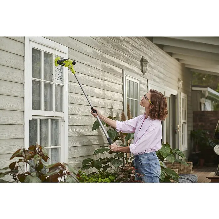 Ryobi 4V USB Akku-Reinigungsbürste RTS4-120G - 4 V, Ohne Akku - Frau reinigt ein schmutziges Fenster mit einem langstieligen, gelb-schwarzen Ryobi Schrubbwerkzeug.