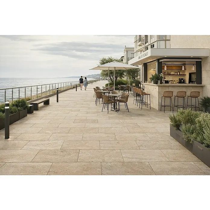 Terrassenfliese Duomo - 60 x 90 x 2 cm, Travertino, Matt - Helle, beigefarbene Außenpflasterfliesen gestalten eine weitläufige Strandpromenade mit Café, Tischen und Gästen.