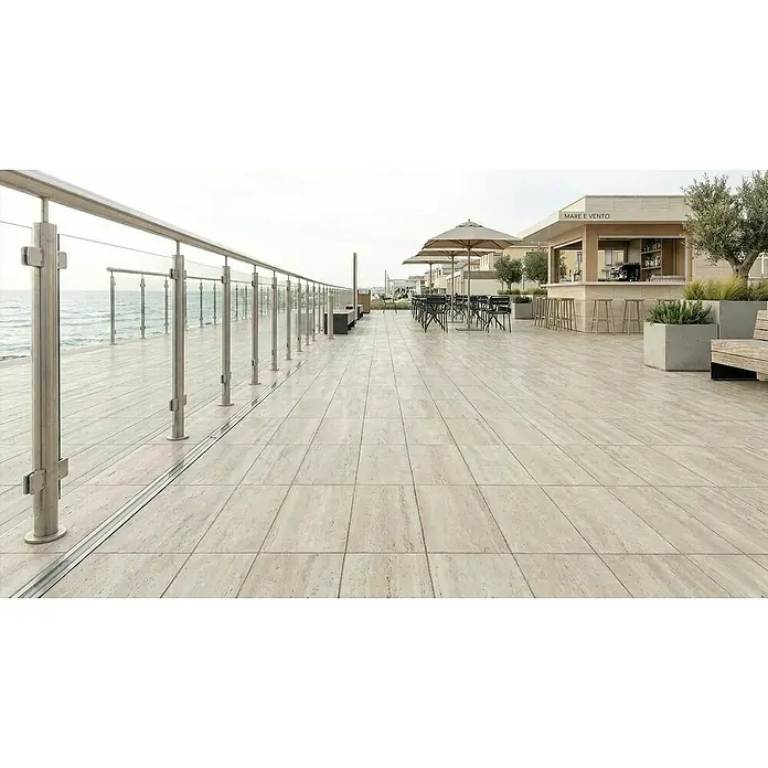 Terrassenfliese Duomo - 60 x 90 x 2 cm, Travertino, Matt - Helle, beigefarbene Terrassenfliesen auf einer Meerblickterrasse mit Bar und Sitzgelegenheiten.