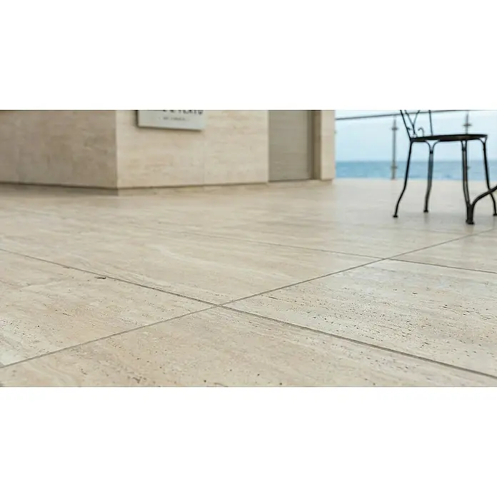 Terrassenfliese Duomo - 60 x 90 x 2 cm, Travertino, Matt - Große, hellbeige Outdoor-Terrassenfliesen in Natursteinoptik auf einem Balkon mit Meerblick.