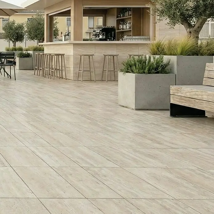 Terrassenfliese Duomo - 60 x 90 x 2 cm, Travertino, Matt - Helle Outdoor-Fliesen in Holzoptik im Großformat auf einer Terrasse mit Bar und Pflanzkübeln.