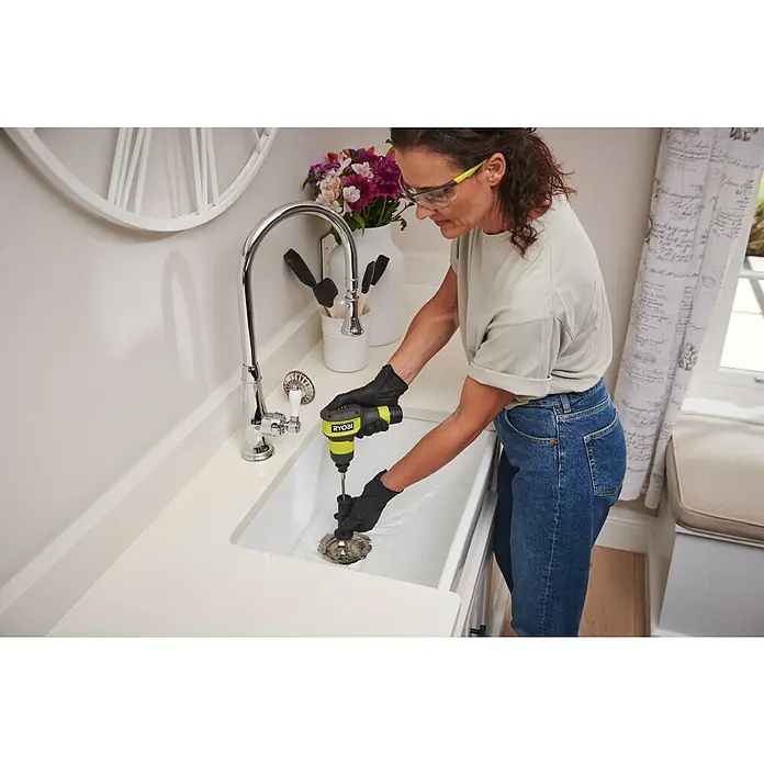 Ryobi 4V USB Akku-Rohrreinigungsgerät RDA4-0 - 4 V, Ohne Akku, Leerlaufdrehzahl: 200 U/min - Gelb-schwarze RYOBI Abflussspirale reinigt einen Küchenspülbeckenabfluss.