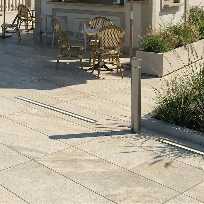 Terrassenfliese Etna - 40 x 80 x 2 cm, Cappucino, Matt - Zwei eingelassene Linearleuchten mit Metallrahmen beleuchten helles Außenpflaster auf einer Terrasse.