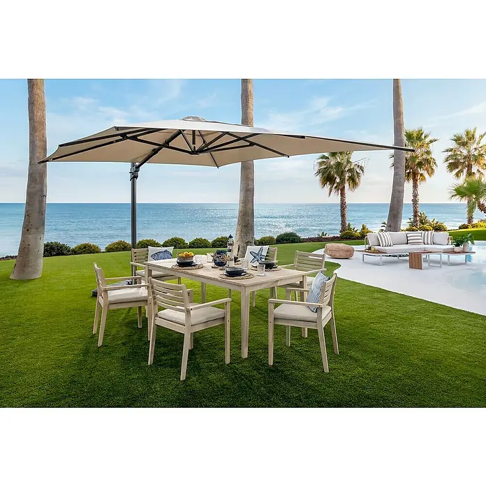 Sunfun Conjunto de muebles Nour mesa rectangular - 7 pzs., Especificación del material, Marrón - Conjunto de comedor exterior con mesa y sillas de madera clara, cojines y gran sombrilla beige, con vistas al mar.