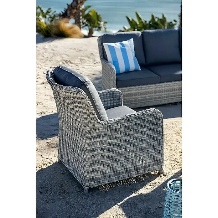 Conjunto de muebles Lodrino - 6 pzs., Aluminio/Olefin, Beige/Gris - Sillón y sofá de exterior de mimbre gris con cojines oscuros, en una playa de arena.