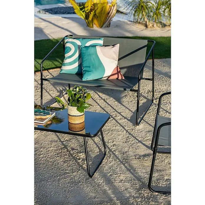 Conjunto de muebles Kateli - 4 pzs., Acero/Textiline, Antracita - Banco de jardín y mesa de centro exterior gris oscuro y negro, con cojines y planta, sobre arena.