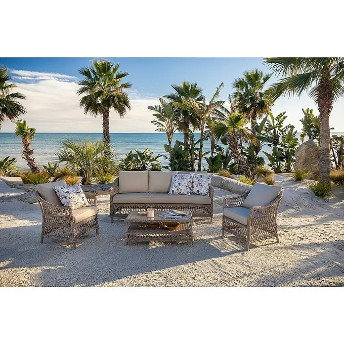 Sunfun Conjunto de muebles Soraya - 4 pzs., Ratán sintético/Aluminio/Poliéster, Beige/Gris - Juego de exterior de mimbre: sofá, dos sillas y mesa de centro con cojines claros, en una playa.