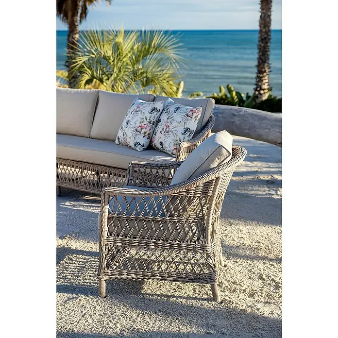 Sunfun Conjunto de muebles Soraya - 4 pzs., Ratán sintético/Aluminio/Poliéster, Beige/Gris - Sofá y sillón de exterior de mimbre gris trenzado con cojines claros en una playa de arena.