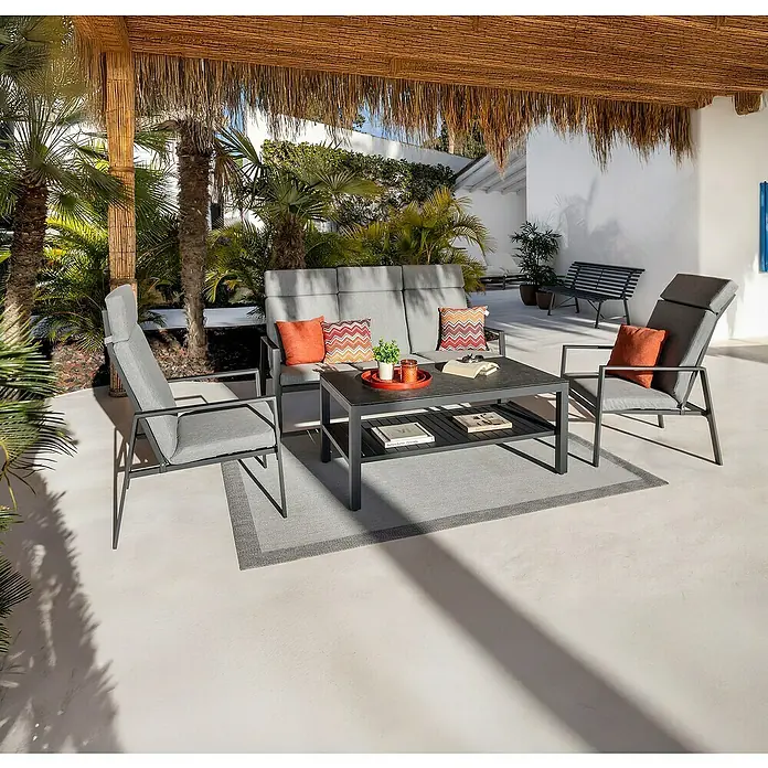 Sunfun Conjunto de muebles Tonini - 4 pzs., Aluminio/Poliéster, Antracita - Moderno conjunto de salón exterior gris con sofá, dos sillas y mesa de centro, acentuado con cojines naranjas, en un patio.