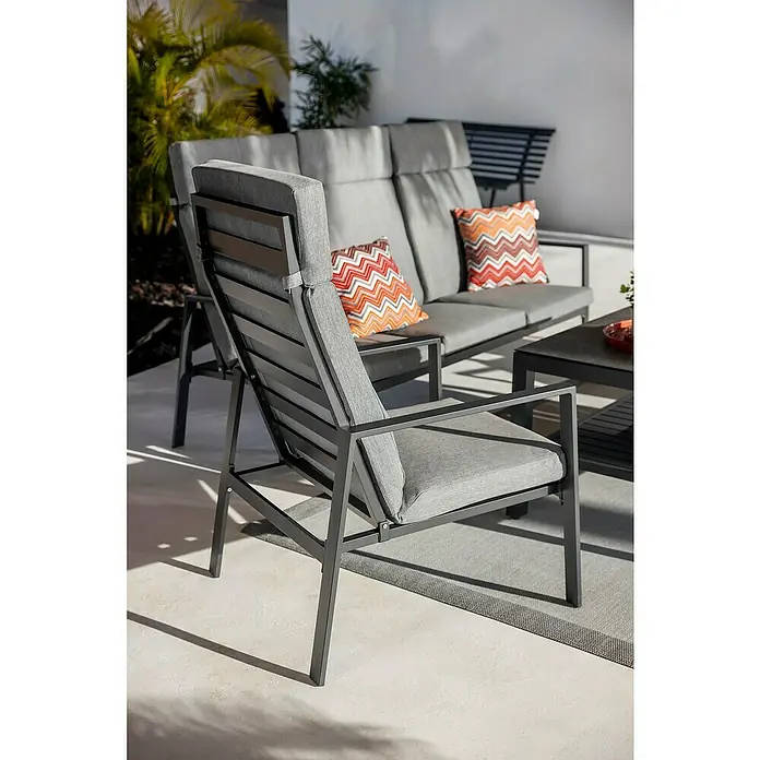 Sunfun Conjunto de muebles Tonini - 4 pzs., Aluminio/Poliéster, Antracita - Sillón y sofá de exterior modernos en gris oscuro con cojines gris claro y almohadas naranjas estampadas en un patio.