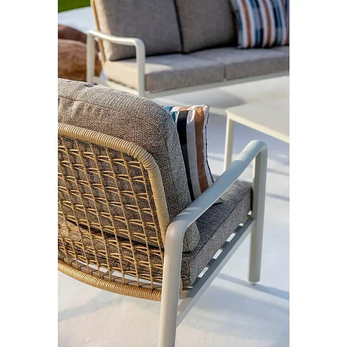 Sunfun Conjunto de muebles Bruna - 4 pzs., Ratán sintético/Aluminio/Poliéster, Beige/Gris - Sillón de exterior con respaldo de mimbre trenado, cojines de tela gris y estructura de metal claro, con sofá a juego al fondo.