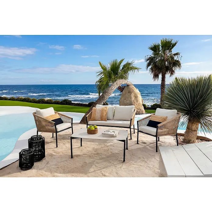 Conjunto de muebles Echo - 4 pzs., Acero/Cuerda, Beige/Negro - Zona de estar exterior con sofá de mimbre beige, dos sillones con cojines crema y mesa de centro clara, sobre arena junto a una piscina.