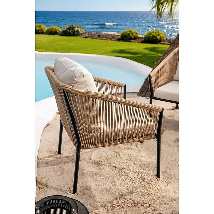 Conjunto de muebles Echo - 4 pzs., Acero/Cuerda, Beige/Negro - Silla de exterior de cuerda trenzada beige con estructura negra y cojines crema sobre arena junto a una piscina y el mar.