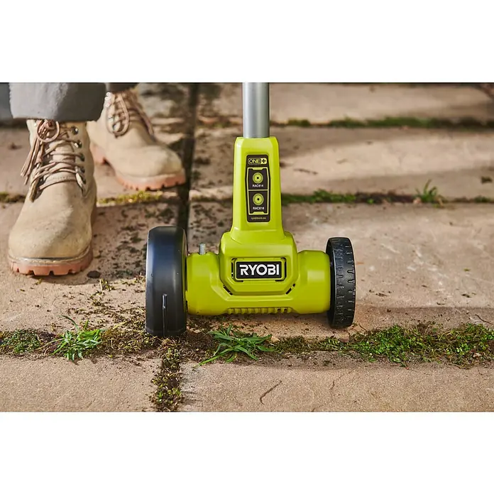 Ryobi ONE+ Akku-Fugenreiniger RY18PCC-0 - Ohne Akku - Ryobi ONE+ limettengrüner Fugenreiniger-Aufsatz mit Rädern, reinigt Unkraut von gepflastertem Boden. Stiefel sichtbar.