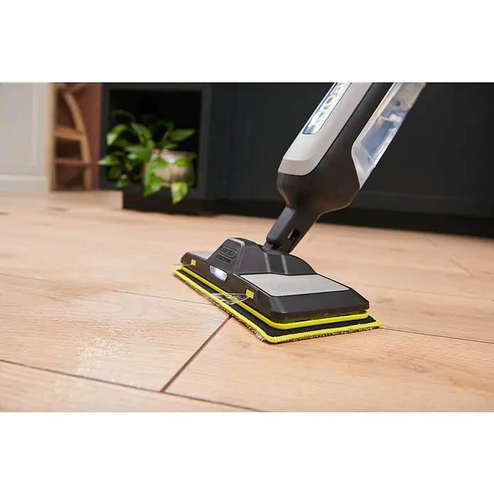 Ryobi Akku-Wischmopp mit Sprühfunktion RSM4-120G - 4 V, 1 Akku, 2 Ah - Ein schwarz-grau-neongrünes Bodenreinigungsgerät sprüht Wasser auf einen hellen Holzfußboden.