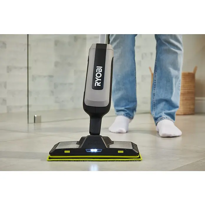 Ryobi Akku-Wischmopp mit Sprühfunktion RSM4-120G - 4 V, 1 Akku, 2 Ah - Ein grauer und schwarzer Ryobi Bodenreiniger mit hellgrünem Pad und Frontlicht wird von einer Person auf einem Fliesenboden benutzt.