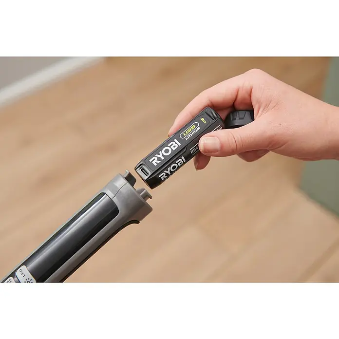 Ryobi Akku-Wischmopp mit Sprühfunktion RSM4-120G - 4 V, 1 Akku, 2 Ah - Eine Hand setzt einen schwarzen Ryobi USB Lithium Akku in ein graues und schwarzes Werkzeug ein.