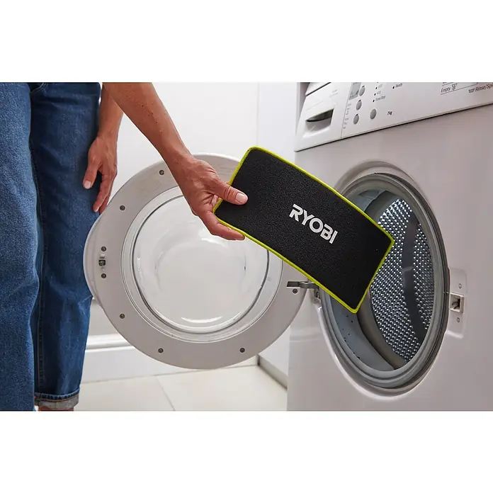 Ryobi Akku-Wischmopp mit Sprühfunktion RSM4-120G - 4 V, 1 Akku, 2 Ah - Schwarzes RYOBI Wischpad mit neongrünem Rand wird in eine Waschmaschine gelegt, was die Waschbarkeit hervorhebt.