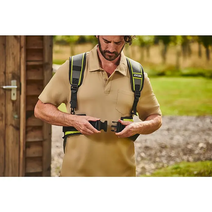 Ryobi Max Power Gürtel RY36BB2PA - Passend für: Zwei 36 V Akkus - Mann in beigem Hemd befestigt einen grauen Ryobi-Gurt mit neongelben Akzenten und schwarzen Schnallen für die Gartenarbeit.