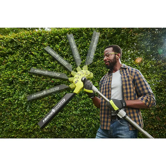 Ryobi ONE+ Teleskop-Heckenschere RY18PHT40A-0 - 18 V, Li-Ionen, Anzahl Akkus: Ohne Akku, Schnittlänge: 40 cm - Mann hält gelben und schwarzen RYOBI 'HEDGE SWEEP' Heckenscheren-Aufsatz mit mehreren Kehrblättern vor einer Hecke.
