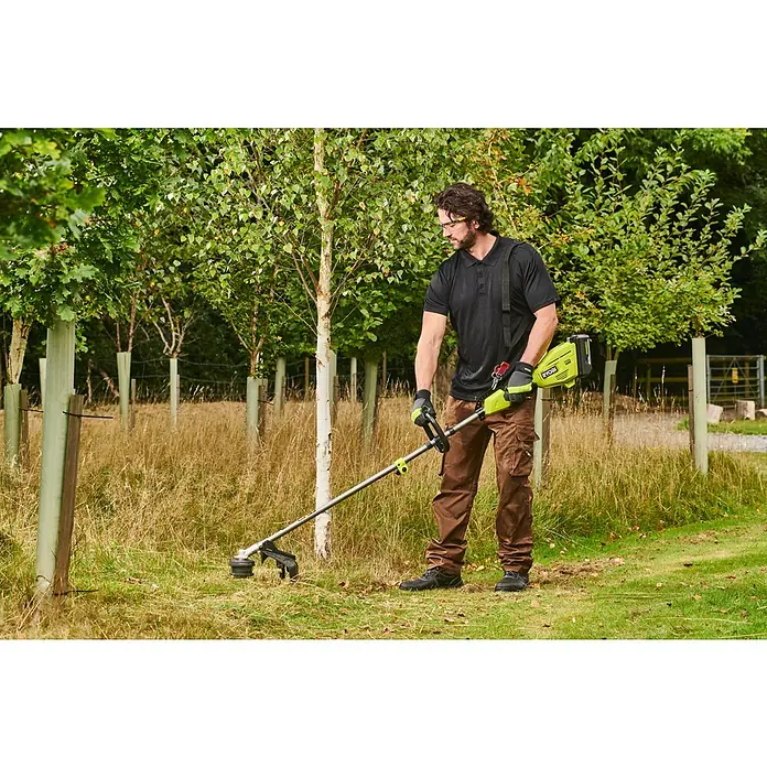 Ryobi Max Power Akku-Rasentrimmer RY36LT38A - 36 V, Li-Ionen, Ohne Akku, Schnittbreite Faden: 38 cm - Mann benutzt einen grün-schwarzen Ryobi Rasentrimmer, um Gras auf einem Feld mit jungen Bäumen zu schneiden.