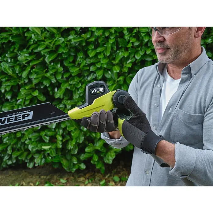 Ryobi ONE+ Teleskop-Heckenschere RY18PHTX45A - 18 V, Li-Ionen, Anzahl Akkus: Ohne Akku - Person mit Handschuhen hält gelb-schwarze Ryobi 18V ONE+ HP Heckenschere mit Debris Remover Klinge.