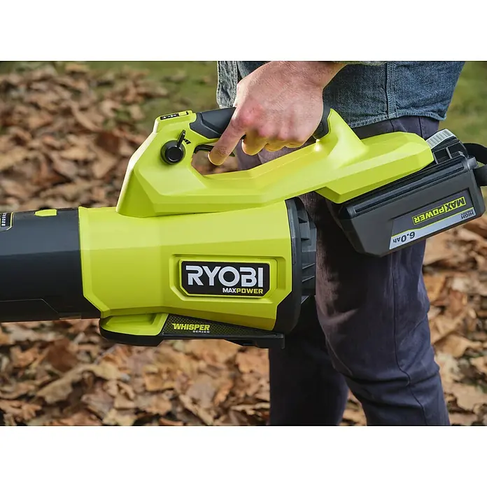 Ryobi Max Power Akku-Gebläse RY36BLXC - 36 V, Ohne Akku, Blasgeschwindigkeit: 289,7 km/h - Eine Person hält einen limettengrünen und schwarzen Akku-Laubbläser im Freien vor herabgefallenen Blättern.